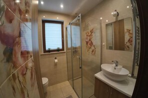 A bathroom with a glass shower enclosure, a toilet, a sink, and a window with blinds. - Holiday Home, 4 Bedrooms, Private Garden (Ustka)