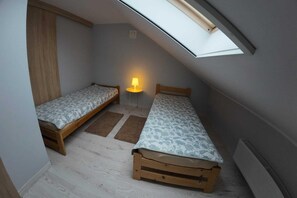 A small attic bedroom with two wooden beds, a skylight, and a floor lamp. - Holiday Home, 4 Bedrooms, Private Garden (Ustka)