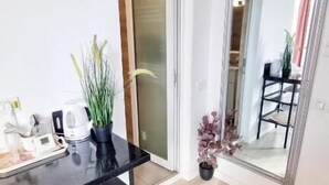 A modern room with a black table, a potted plant, and a mirror reflecting a dining area.
