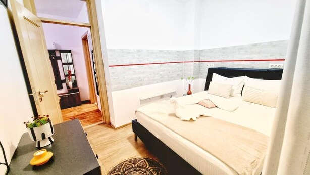 A bedroom with a bed, bedside table, and a small potted plant.