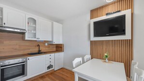 Een moderne keuken met witte kasten, een inbouwoven en een houten aanrecht.