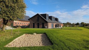 Ein modernes Gebäude mit geneigtem Dach und Ziegelwänden, umgeben von einem gepflegten Rasen und einem Kiesplatz.