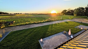 Eine Bauernlandschaft mit Sonnenuntergang, offenen Feldern und einem befestigten Weg.