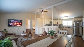 A modern living room with a TV, seating, and a dining area.