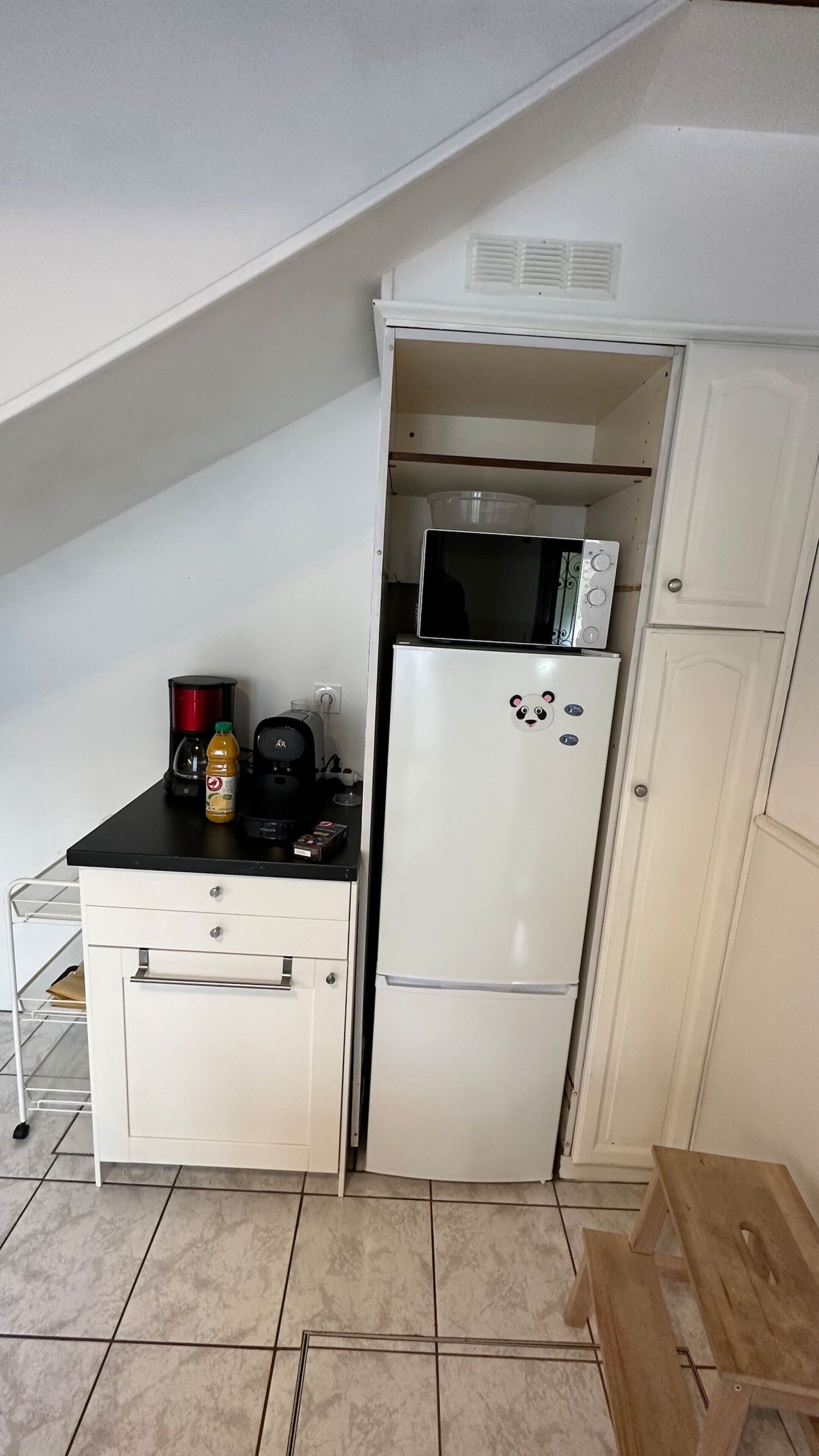 A compact kitchenette with a white refrigerator, a microwave, a coffee maker, and a small countertop.
