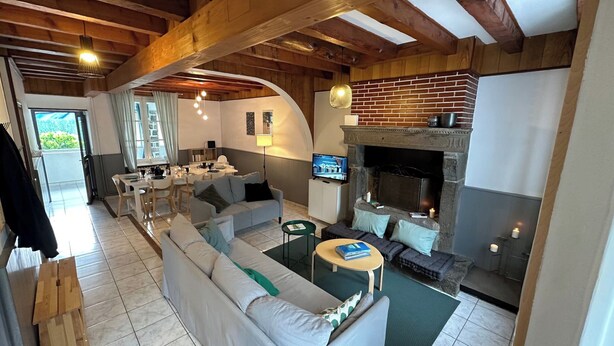 A modern living room with a fireplace, a dining area, and a TV. - Centrally Located Villa in Mont-dore (La Bourboule)