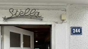 A white door with a black metal gate and a sign above it that reads "Stella". A blue house number sign with the number 244 is visible on the wall to the right. - Centrally Located Villa in Mont-dore (La Bourboule)