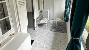 A room with a white bathtub, a bench, and a small table with a rug. - Centrally Located Villa in Mont-dore (La Bourboule)
