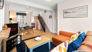 Ein modernes Wohnzimmer mit Sofa, Couchtisch und Fernseher. Eine Treppe führt zu einer weiteren Ebene.