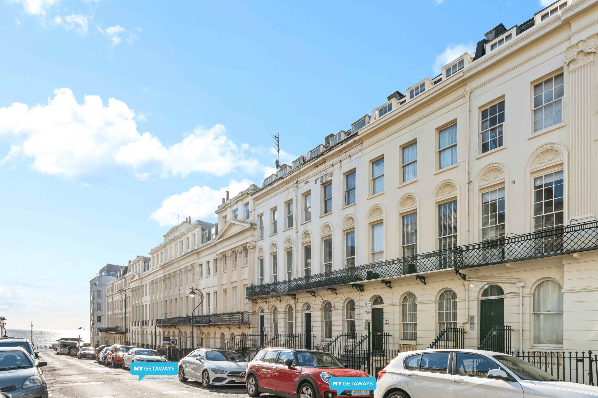 A row of classic European-style buildings with uniform architecture, featuring balconies and large windows.