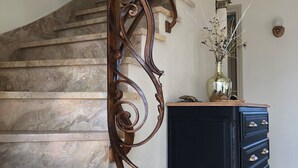 A marble staircase with ornate metal railings, a black dresser with drawers, and a vase with dried flowers on top. - Large, spacious Germaine house in a quiet location 10 minutes from the sea. (Sibiril)