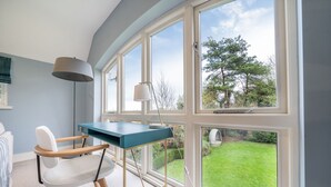 A room with a desk, chair, and large windows offering a view of a garden. - Orchard House 5 bedrooms - sleeps 10 guests  in 5 bedrooms (Burnham Market)