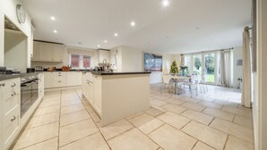 A spacious kitchen with white cabinetry, a central island, and a dining area with a view to the outdoors. - Orchard House 5 bedrooms - sleeps 10 guests  in 5 bedrooms (Burnham Market)