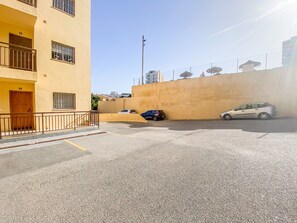 A residential street with a yellow building, a gated parking area, and a clear sky. - Apartment in Benalmadena With Sea Views (Benalmádena)