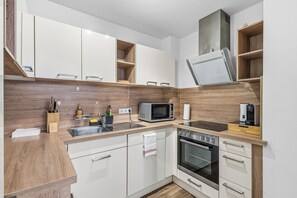 Eine moderne Küche mit weißen Schränken, einer Holz Arbeitsplatte, einer eingebauten Mikrowelle, einem Herd und einem Spülbecken.