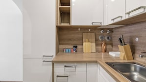 Una cocina moderna con armarios blancos, una encimera de madera y un fregadero de acero inoxidable.