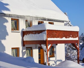 A snow-covered house with a wooden pergola in front. - Haus De Kleene & Gruusse in Mildenau (Mildenau)