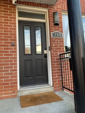 A brick building with a black door, a doormat, and a mailbox. - Cozy Downtown Toronto Retreat Near King W & Queen W Life (Toronto)