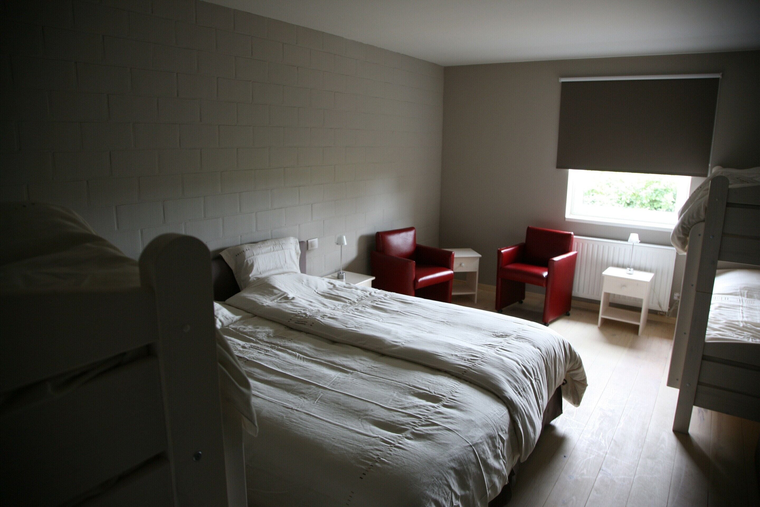A bedroom with a bed, a desk, and a chair.