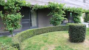 A building with a brick facade, a neatly trimmed hedge, and a small tree in the foreground. - Countryside Holiday Home (Alveringem)