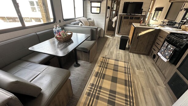 A compact RV interior with a dining area, seating, kitchenette, and a TV. - Quiet retreat on beautiful horse farm (Ocala)