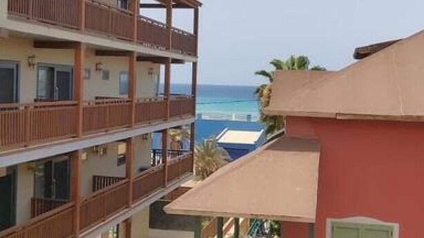 Un edificio de varios pisos con balcones que dan a una playa.
