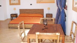 Un dormitorio con una cama, una mesa de madera y dos sillas.