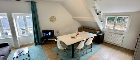 A modern living room with a dining area, a TV, and a staircase.