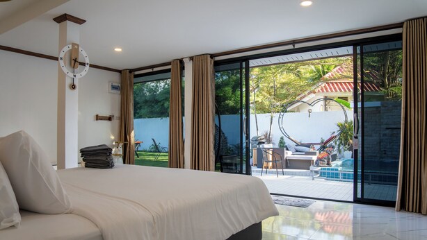 Une chambre dotée d’un grand lit, donnant sur une piscine extérieure, et possédant une porte-fenêtre coulissante.