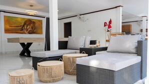 Un espace de vie moderne comprenant un canapé, deux poufs ronds en osier, une table à manger et un tableau représentant un tigre.