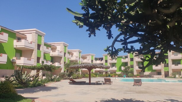 Een resort met meerlaags gebouwen, een centraal gelegen zwembad en terrasjes.