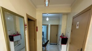 A hallway with a large mirror, a chandelier, and a door leading to a room with a bed and a small table. - 2 balcony rooms in Mabrouka  5 minutes from Guéliz (Marrakech)