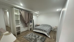 Un dormitorio con una cama, una mesita de noche, una lámpara, un armario y una alfombra gris.