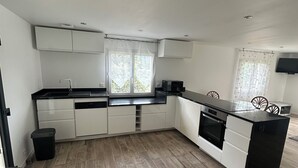 Una cocina moderna con armarios blancos, encimera negra y horno integrado.