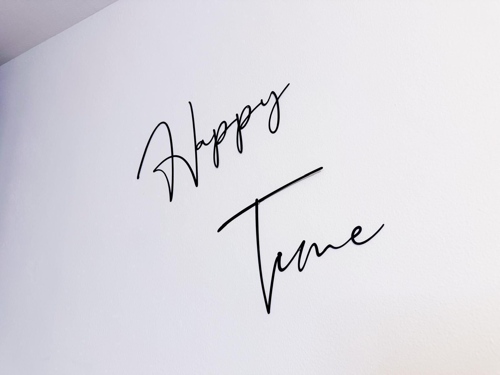 Un mur sur lequel est écrit en lettres cursives : « Happy Time ».