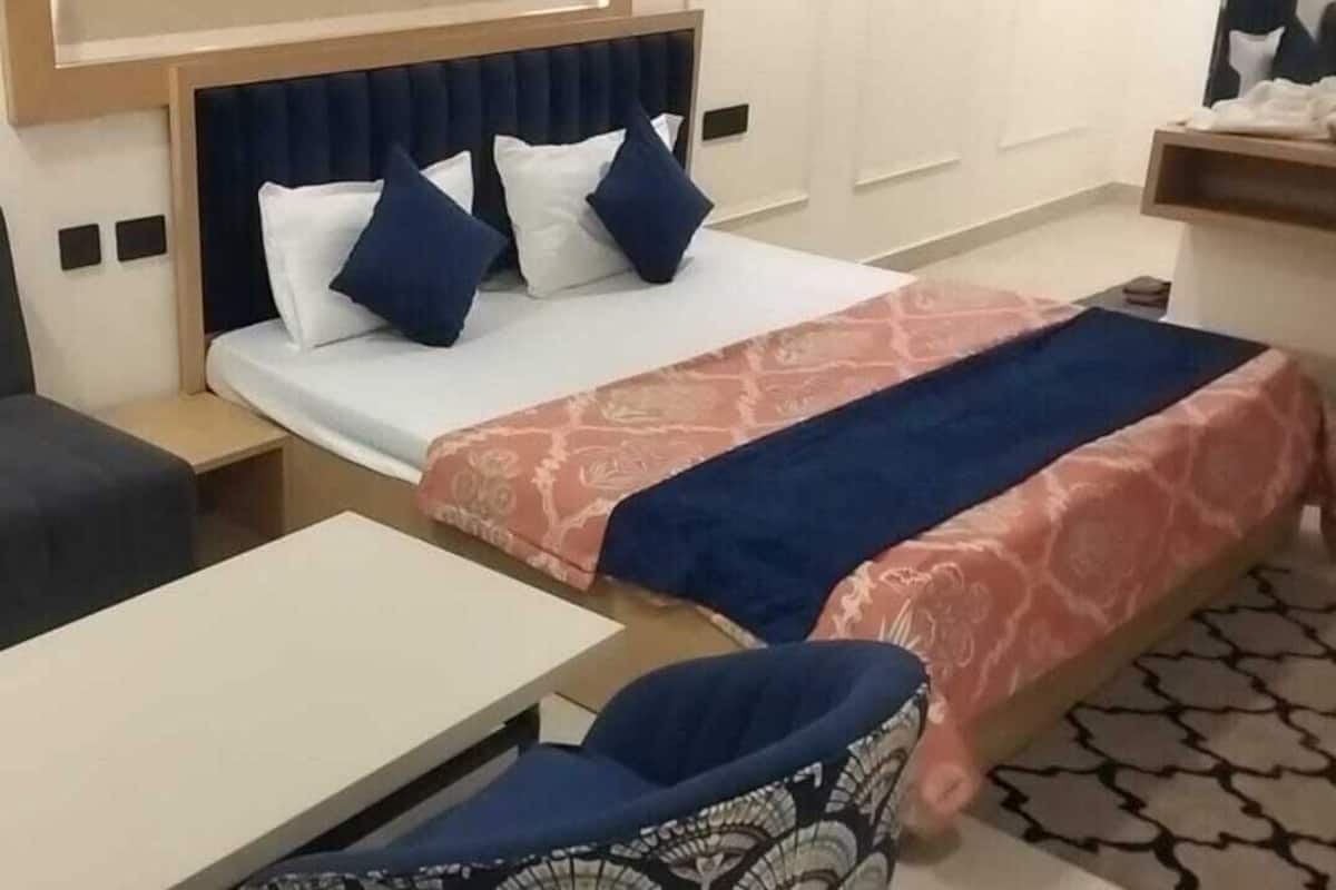 A hotel room with a bed, a desk, a chair, and a small table.