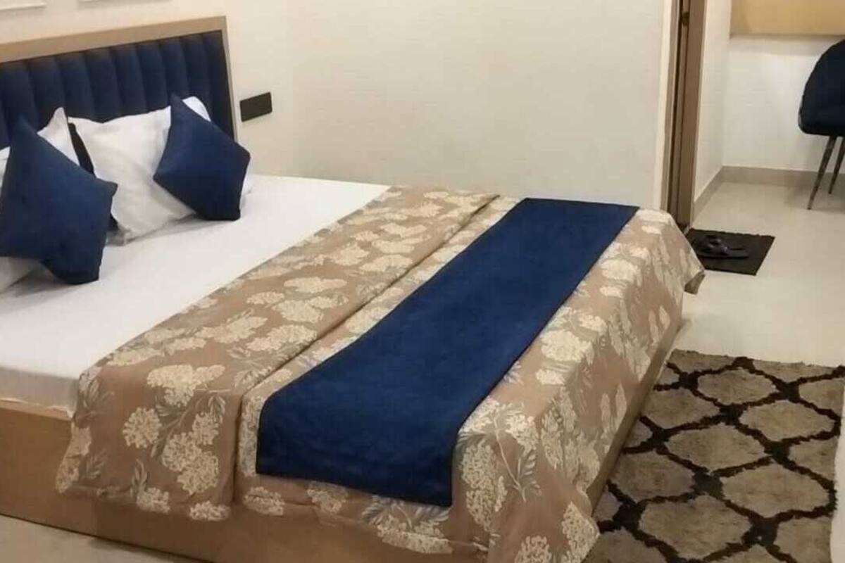 A hotel room with a bed, a chair, a desk, and a TV.