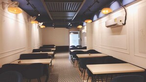 A restaurant interior with booths and tables, patterned flooring, and pendant lighting. - The Garrison Hotel (Meerut)