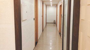A long, narrow hallway with wooden doors and white walls. - The Garrison Hotel (Meerut)