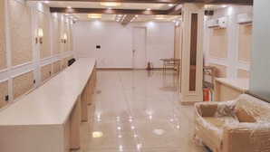 A spacious hotel lobby with a long reception desk, a cushioned seating area, and a chandelier. - The Garrison Hotel (Meerut)