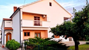 A two-story building with a balcony on the second floor, a small window on the upper floor, and a door on the ground floor. - Apartment Gina in Zaton (Nin)