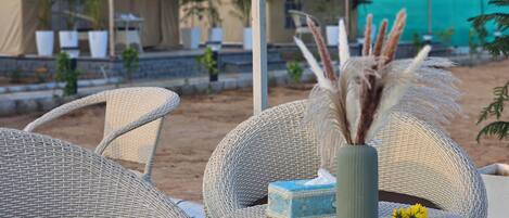 Wicker furniture, a vase with dried plants, and a small blue box on a table.