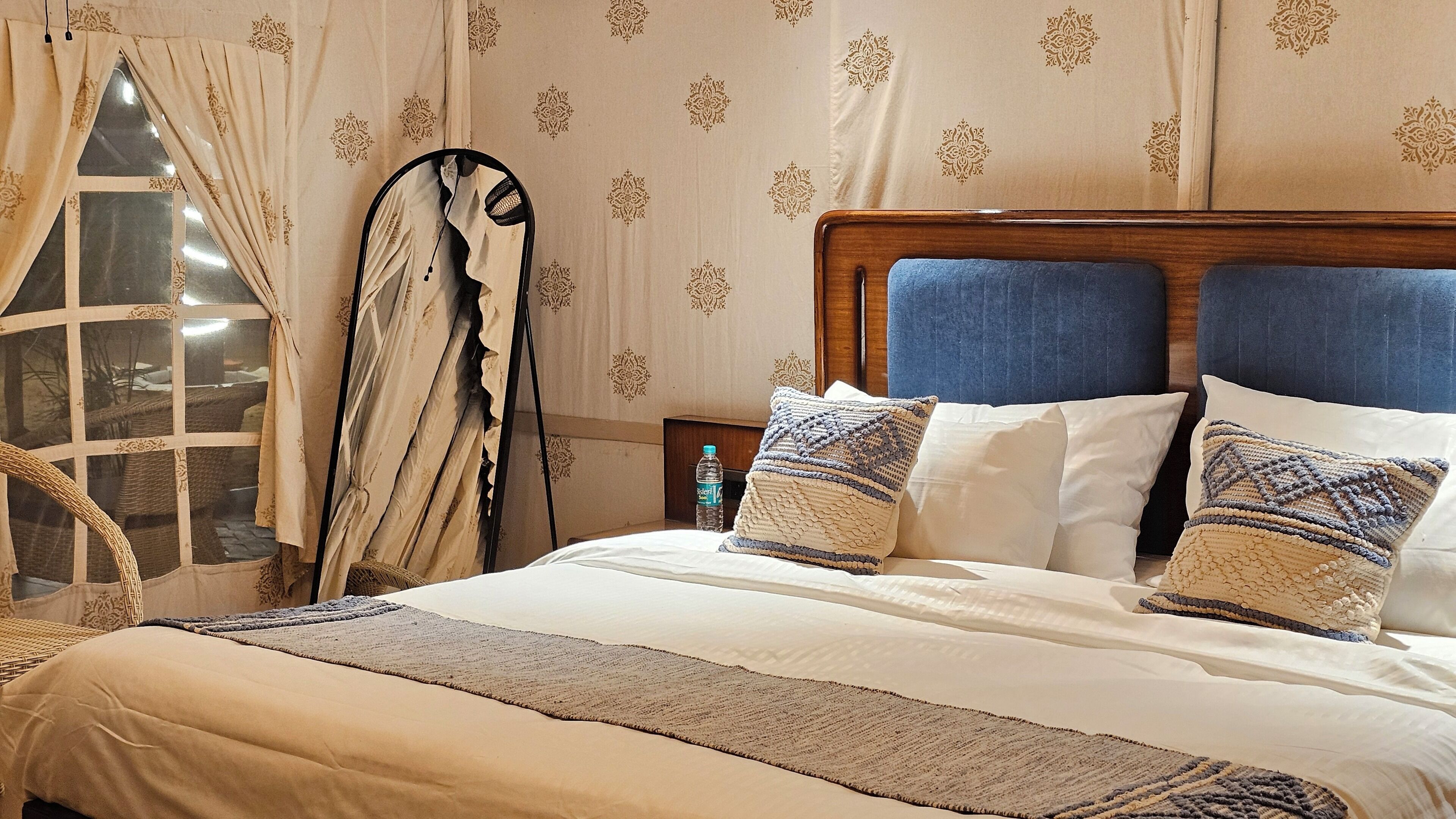 A bed with white linens, a blue headboard, and patterned pillows.