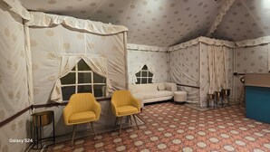 A room with a patterned carpet, a sofa, two yellow chairs, a small table, and a blue counter. - Mayura Retreat (Danta Ramgarh)