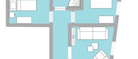 A floor plan of a hotel room with a bed, a desk, a chair, a small table, a sofa, and a bathroom with a toilet and sink.