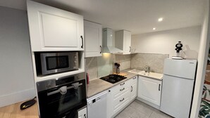 Una cucina compatta con mobili bianchi, un forno a microonde, fornelli, forno e frigorifero.
