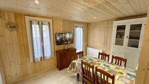 A wooden-paneled room with a dining table, chairs, a TV, and a cabinet. - Breezy Nook Near the ski Resort (Mont-Dore)