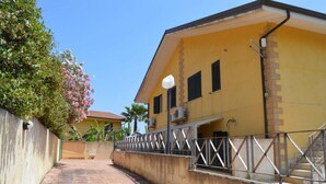 A yellow building with a staircase leading to a door, surrounded by a metal railing and a concrete wall. - Holiday Properties Sicilian Breeze2 (Lido di Noto, Italy)