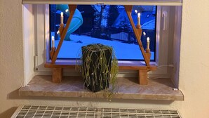 Una ventana con vistas a un paisaje nevado, un candelabro decorativo y una planta en un estante.