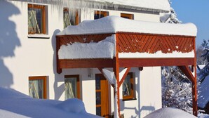 Una casa cubierta de nieve con una pérgola de madera al frente.